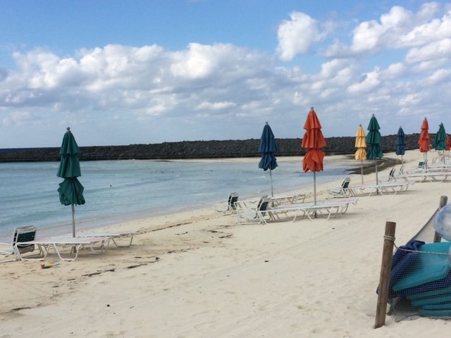 The private beach on Castway Cay. The beach is empty but for a few umbrellas and lounge chairs. The beach os for guests in the private Cabanas.